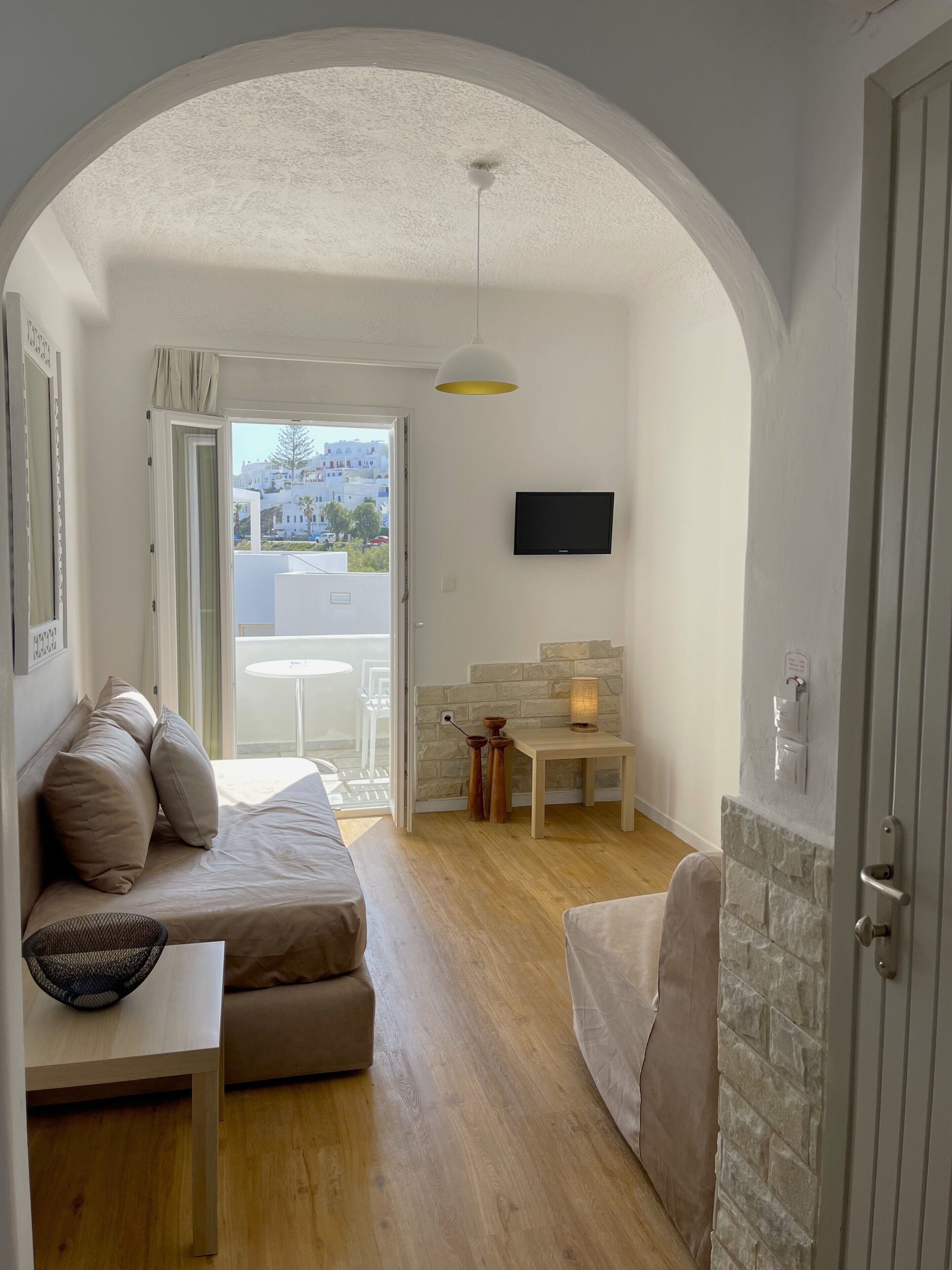 Un salon moderne avec un canapé, une petite table et un téléviseur fixé au mur.