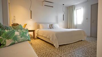 A bedroom with a bed, a bedside table, an air conditioner, a window with curtains, and a patterned floor.