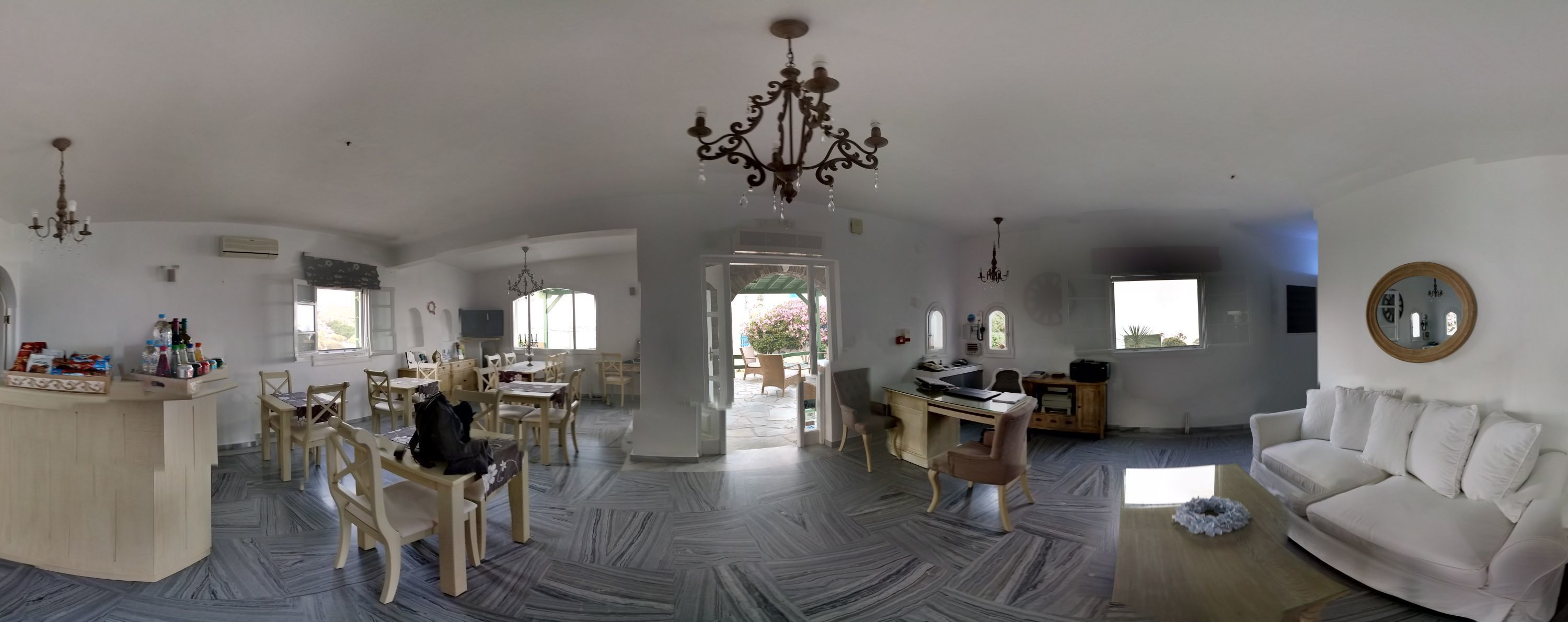 Amplia sala de estar con un sofá blanco, una mesa de comedor con sillas y una lámpara de araña.