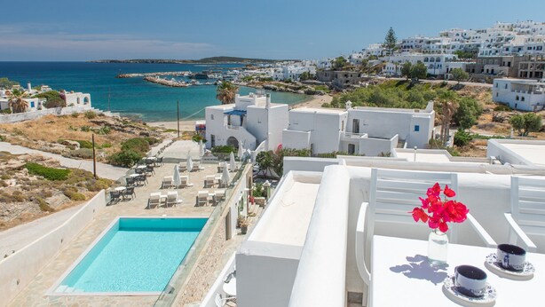A rooftop pool with clear blue water, white buildings, and a view of the sea and distant islands. - Adonis Hotel & Apartments (Paros)