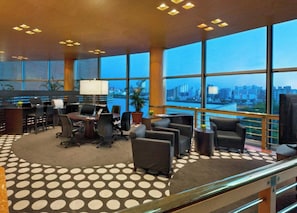 A modern hotel lobby with a round table, seating, and a city view through large windows. - Sheraton Cordoba Hotel (Córdoba)