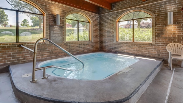 A spa area with a hot tub, large arched windows, and a brick wall.