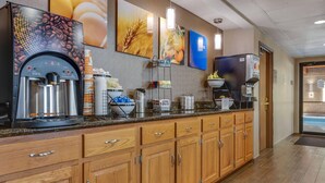 A hotel kitchen with a coffee machine, a water dispenser, and a fruit display.