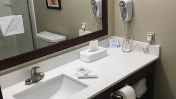 Un baño con lavamanos blanco, un espejo, secador de pelo y un inodoro.