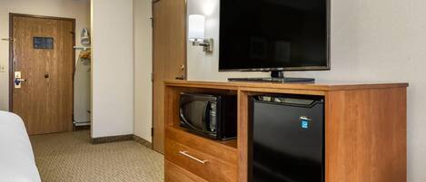 Habitación de hotel con un armario de madera, televisor de pantalla plana, microondas y refrigerador.