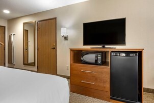 Habitación de hotel con cama, televisión, microondas y refrigerador.