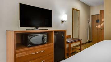Ein Hotelzimmer mit Flachbildfernseher, Mikrowelle, Kühlschrank, Holzschreibtisch, Stuhl und Kleiderschrank.