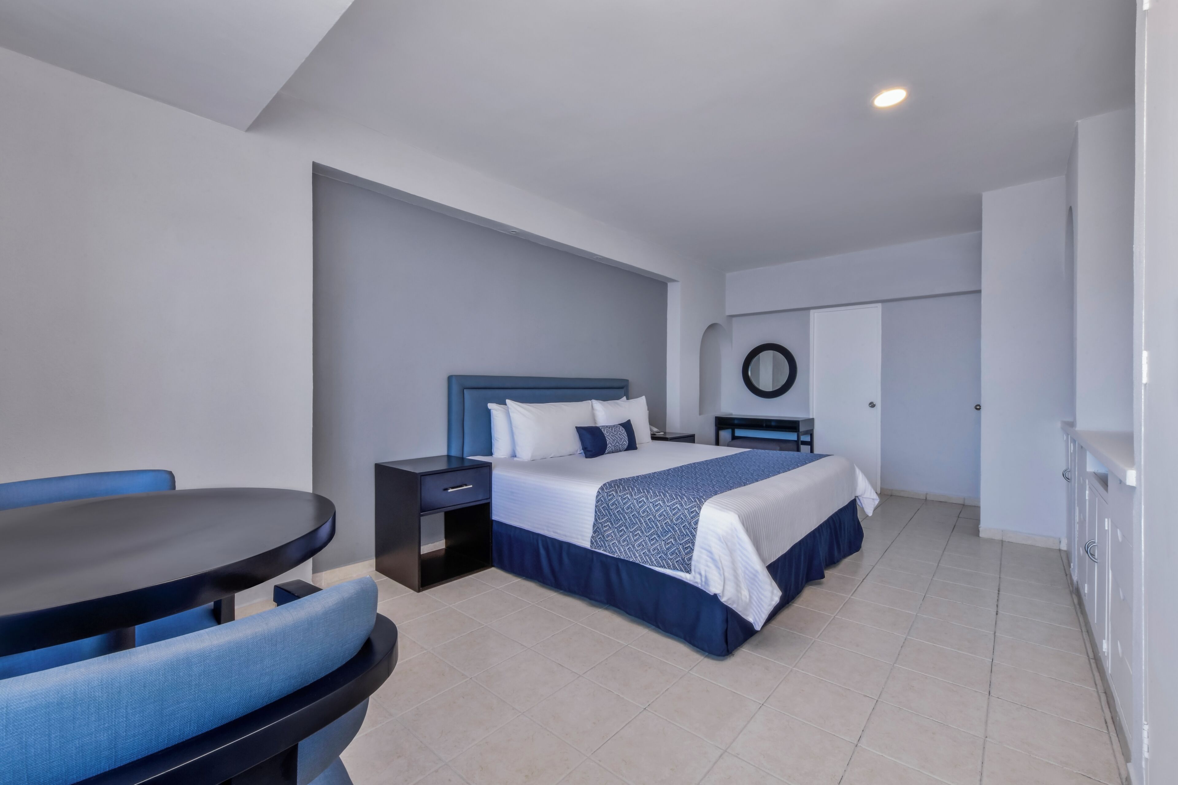 A modern hotel room with a bed, a desk, and a chair.