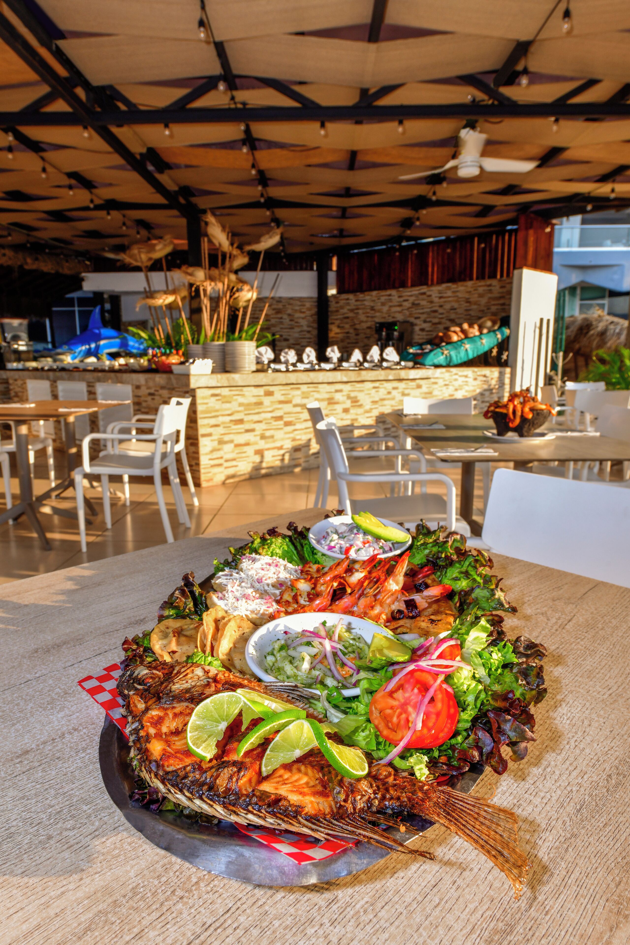 A seafood platter with a variety of vegetables and a side salad on a table in a restaurant setting.