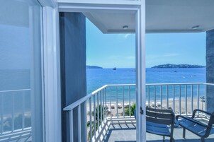 Un balcón con vista al mar, una silla y una mesa.