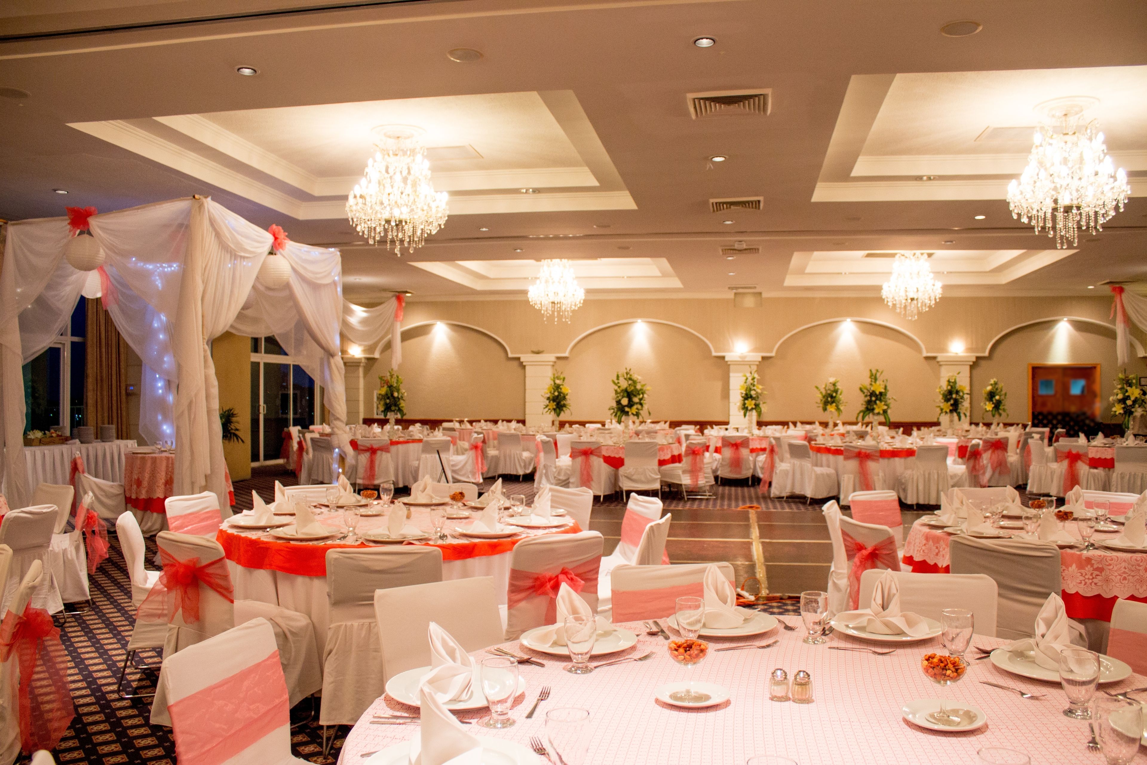 A banquet hall with round tables, white tablecloths, and red sashes.