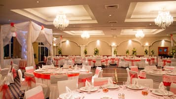 A banquet hall with round tables, white tablecloths, and red sashes.