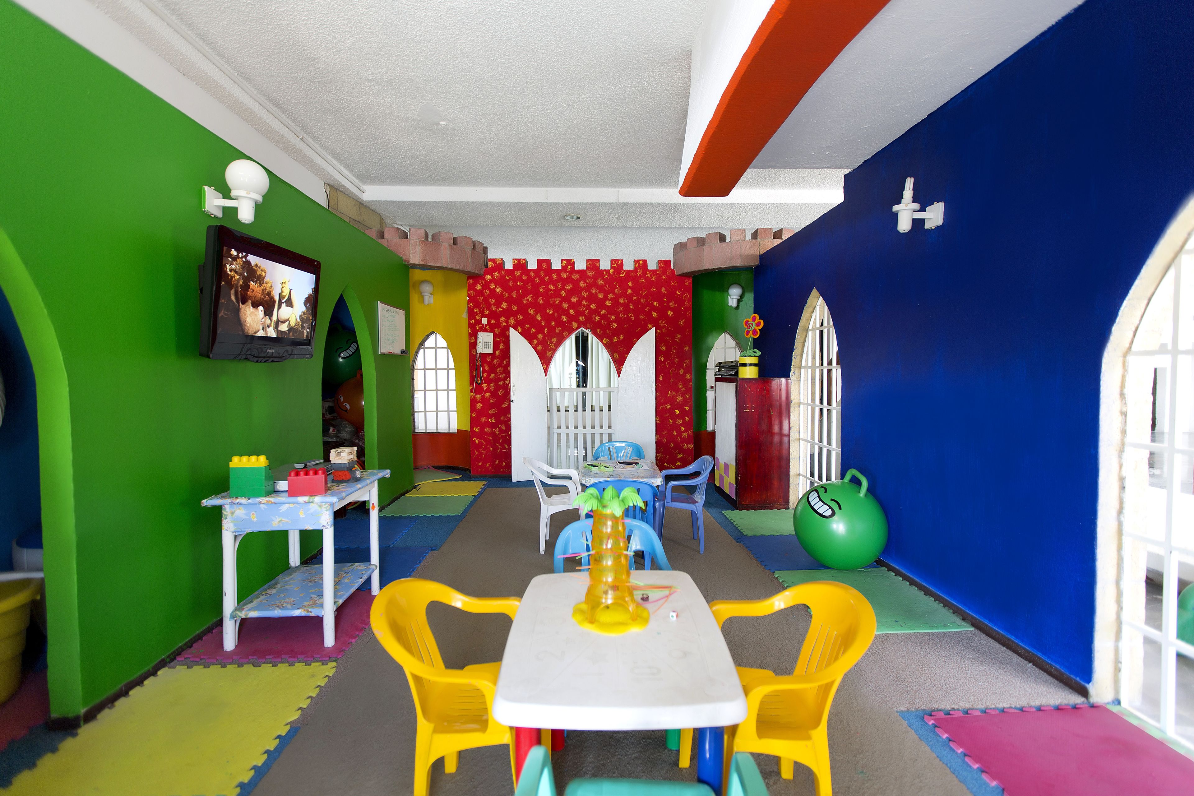 A playroom with a table and chairs, a television, and colorful walls.