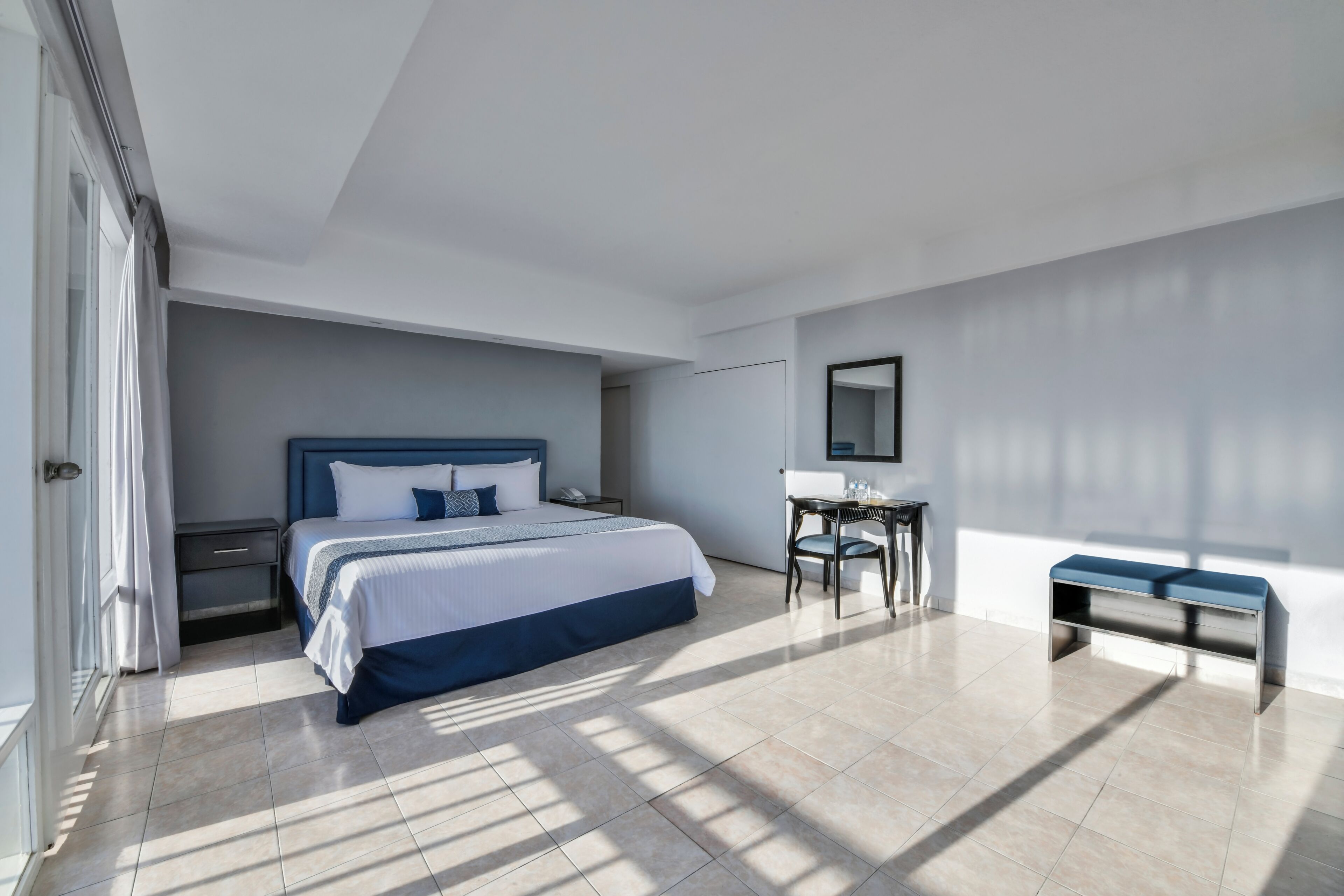 Une chambre d’hôtel moderne, dotée d’un grand lit, d’un bureau et d’une banquette.