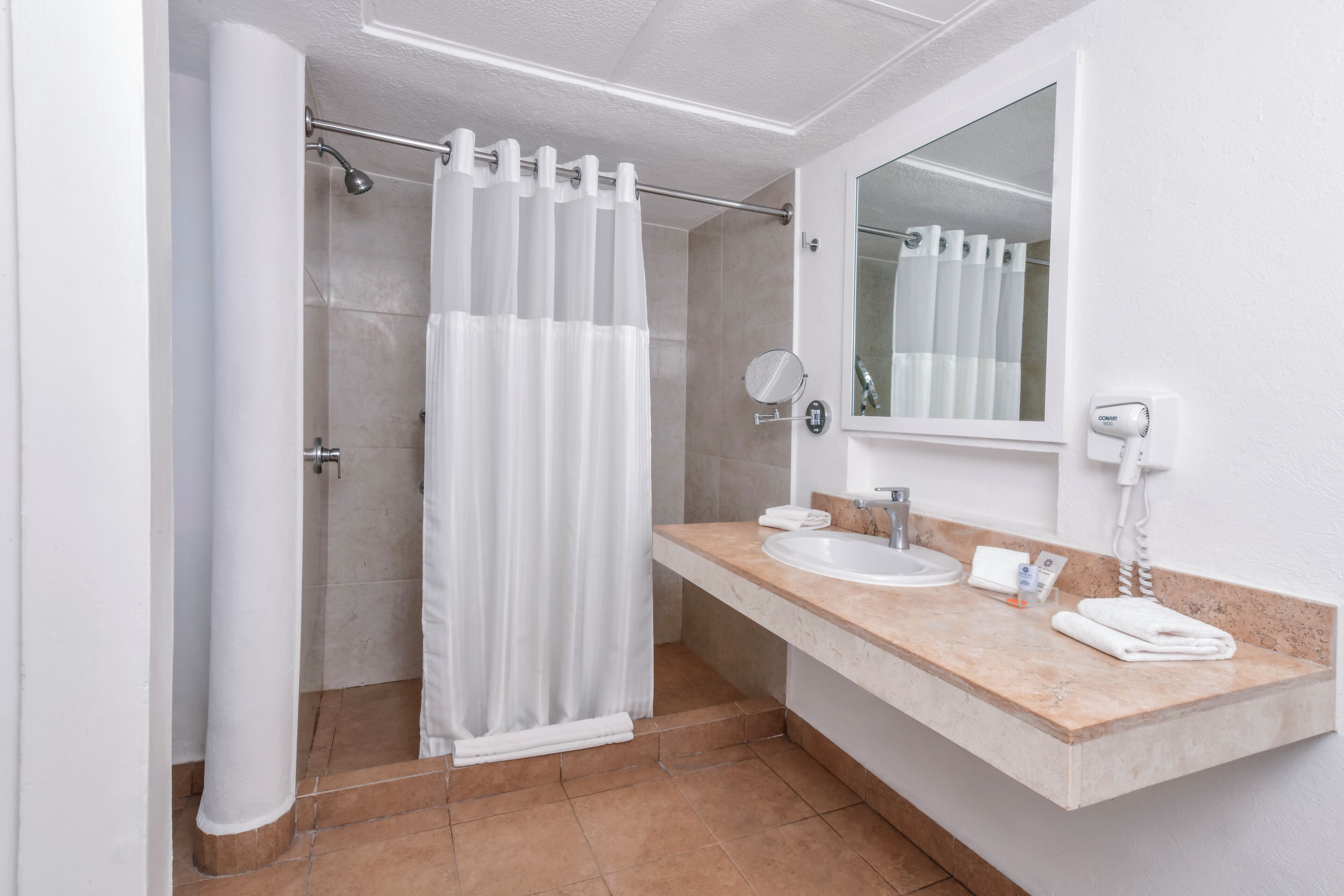 A bathroom with a shower, a sink, a mirror, and a towel rack.