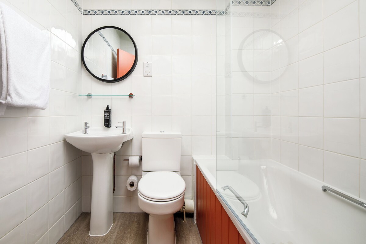A modern bathroom with a white sink, toilet, and bathtub.