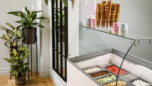 A buffet area with various food options, a glass display case, and decorative wall lights. - ibis Styles Bournemouth (Bournemouth)