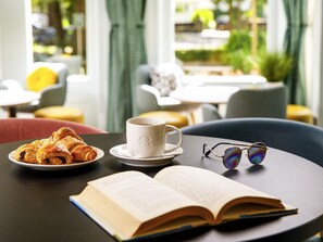 A table with a cup, a book, and pastries. - ibis Styles Bournemouth (Bournemouth)