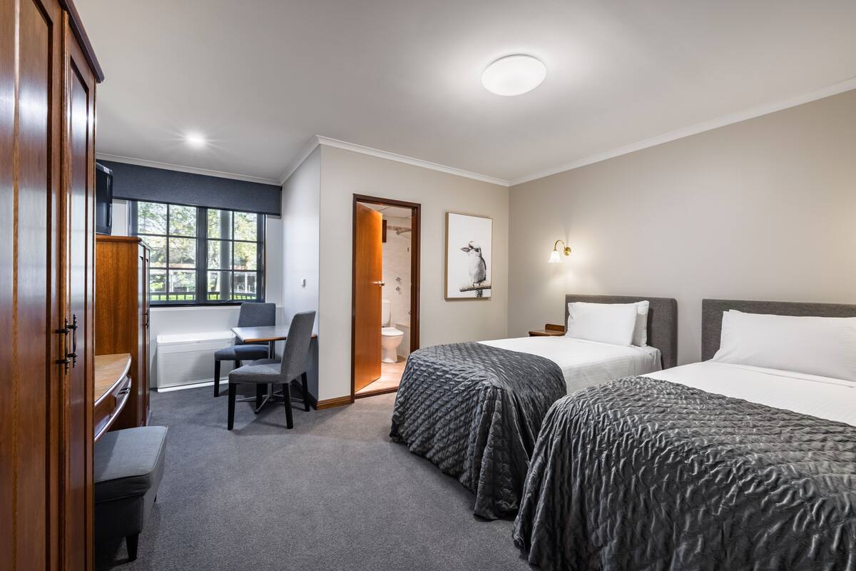 Una habitación de hotel con dos camas, un escritorio, una silla y un armario.