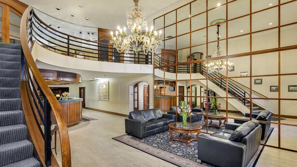 A spacious lobby with a grand staircase, leather seating, and a chandelier. - Adelaide Inn (North Adelaide)