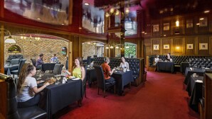 A restaurant with a brick wall, wooden paneling, and a red carpeted floor. - Adelaide Inn (North Adelaide)