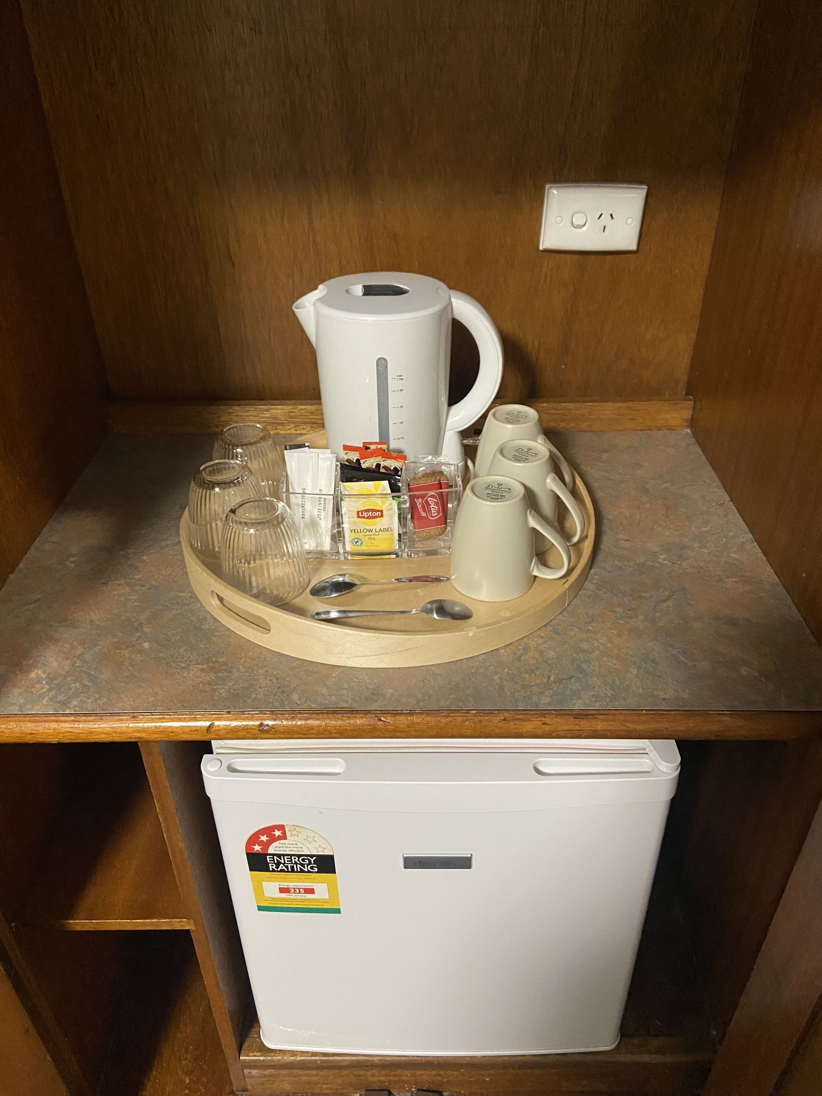 A kitchenette with a coffee maker, cups, a toaster, and a small refrigerator.