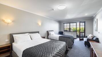 Una habitación de hotel moderna con dos camas, un sofá, un escritorio y un ventanal grande.