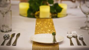 Una mesa dispuesta con un plato blanco, cubiertos y un mantel decorativo dorado.