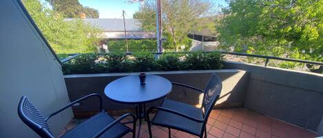 Eine kleine Terrasse mit einem runden Tisch und zwei Stühlen.