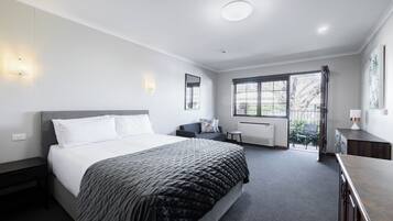Een moderne slaapkamer met een groot bed, nachtkastjes, een zithoekje en uitzicht op de omgeving.