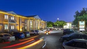 A hotel with a parking lot, multiple cars, and a building with illuminated windows and a signboard. - Adelaide Inn (North Adelaide)