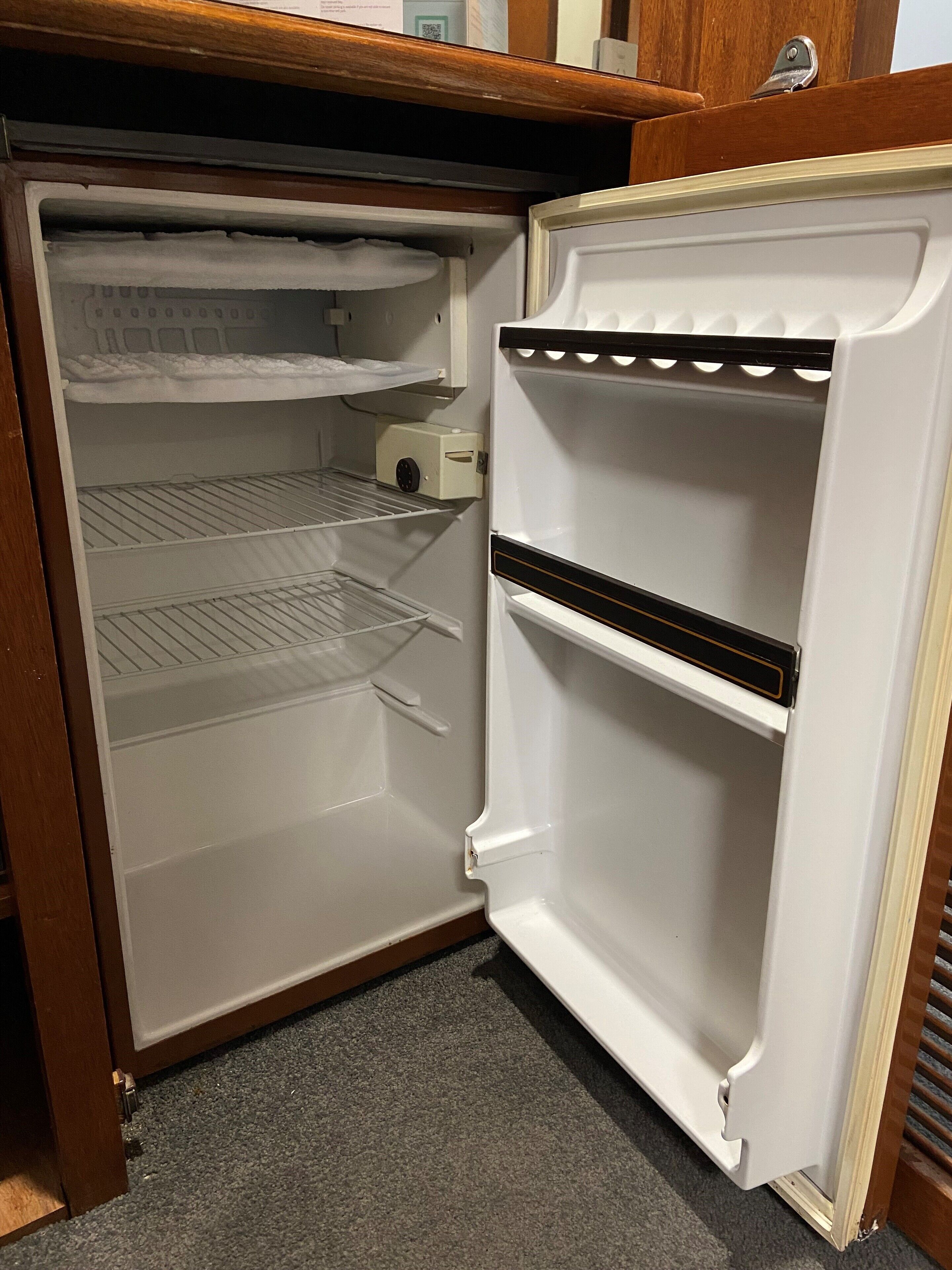 An open refrigerator with three shelves and a freezer compartment.