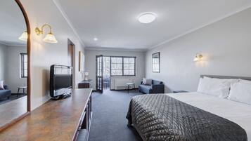 Une chambre d’hôtel avec un grand lit, une télévision, un bureau et un miroir.