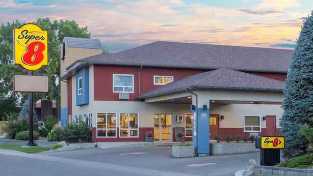A Super 8 motel with a red and beige exterior, a covered entrance, and a parking lot. - Super 8 by Wyndham Lethbridge (Lethbridge)