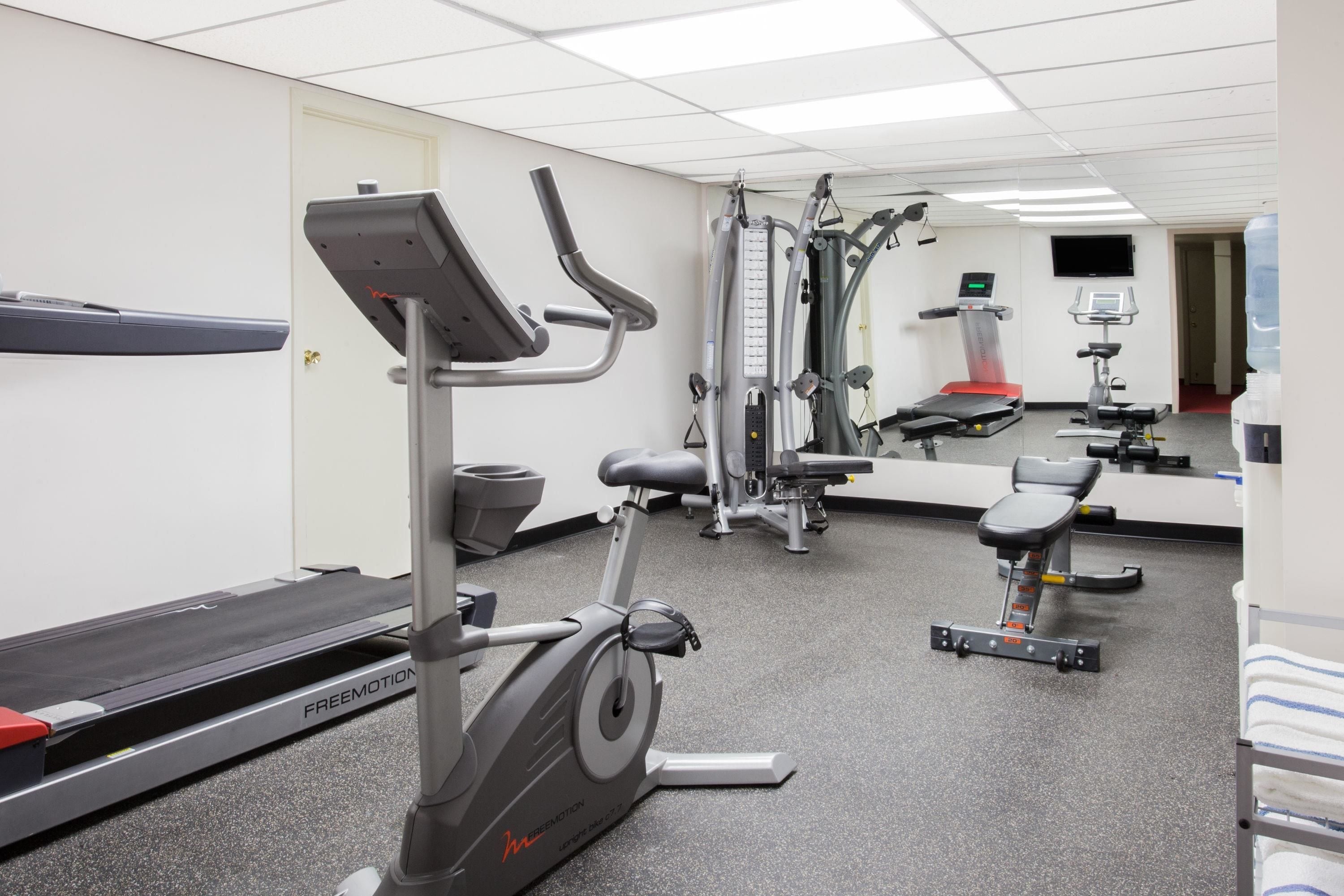 Ein Fitnessraum mit Laufbändern, Crosstrainern und Krafttrainingsgeräten.