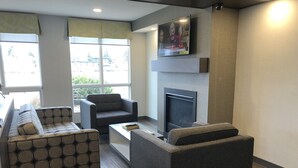 A modern living room with a sofa, armchair, and a fireplace. - Super 8 by Wyndham Lethbridge (Lethbridge)