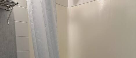 Un baño con ducha, inodoro y perchero para toallas.