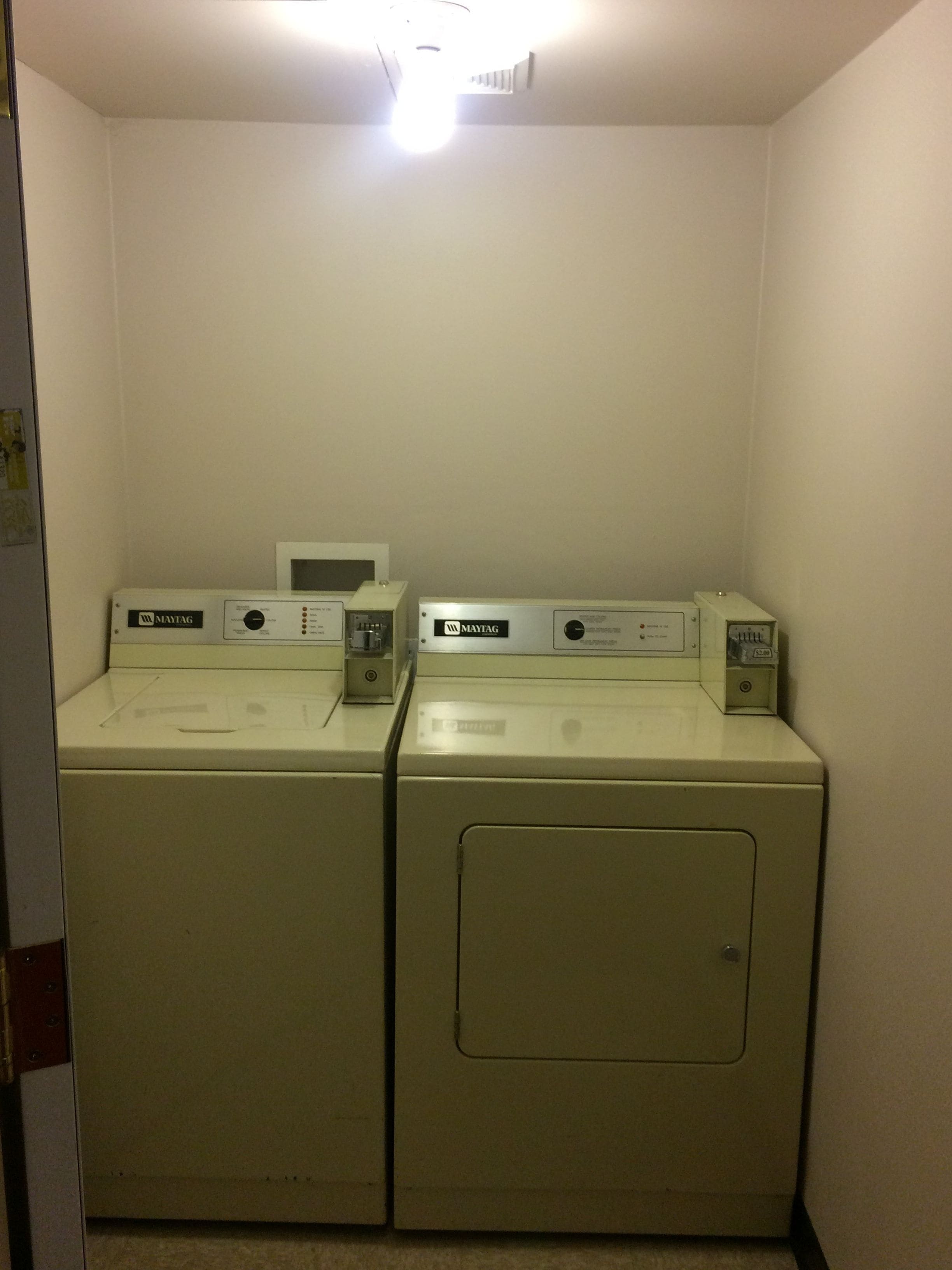 Ein Waschraum mit zwei Maytag Frontlader-Waschmaschinen und einer Mikrowelle darüber.