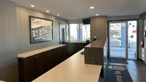 A reception area with a long counter, a mounted television, and a framed picture on the wall. - Super 8 by Wyndham Lethbridge (Lethbridge)