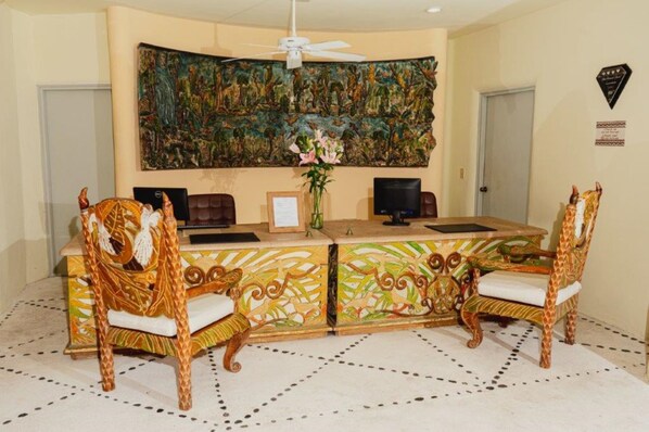 A reception area with a large mural, two giraffe-themed chairs, a desk with a computer, and a framed certificate on the wall. - Quinta Real Huatulco (Santa María Huatulco)