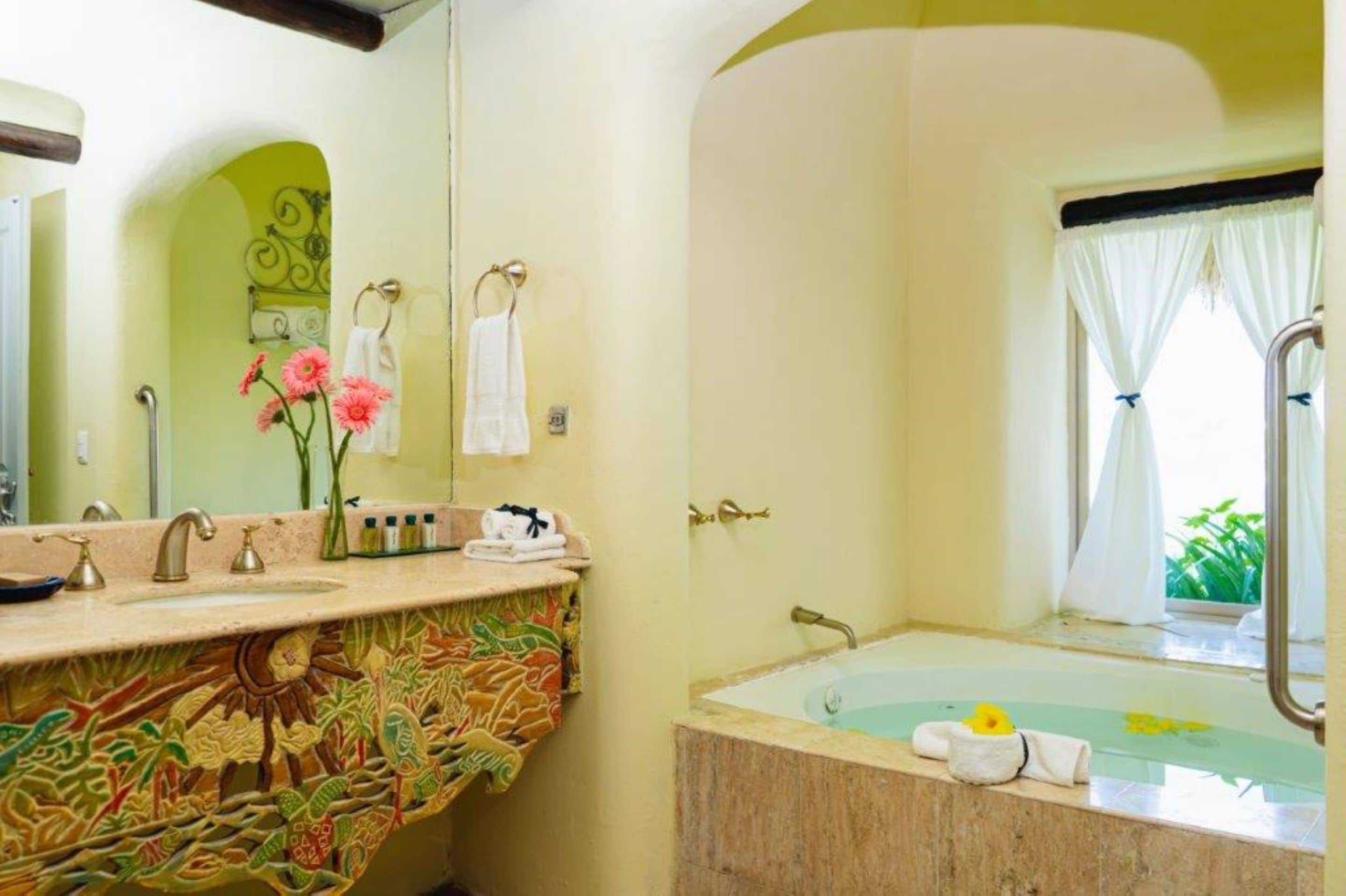 A bathroom with a large mirror, a sink with a decorative tile backsplash, and a bathtub with a window view.