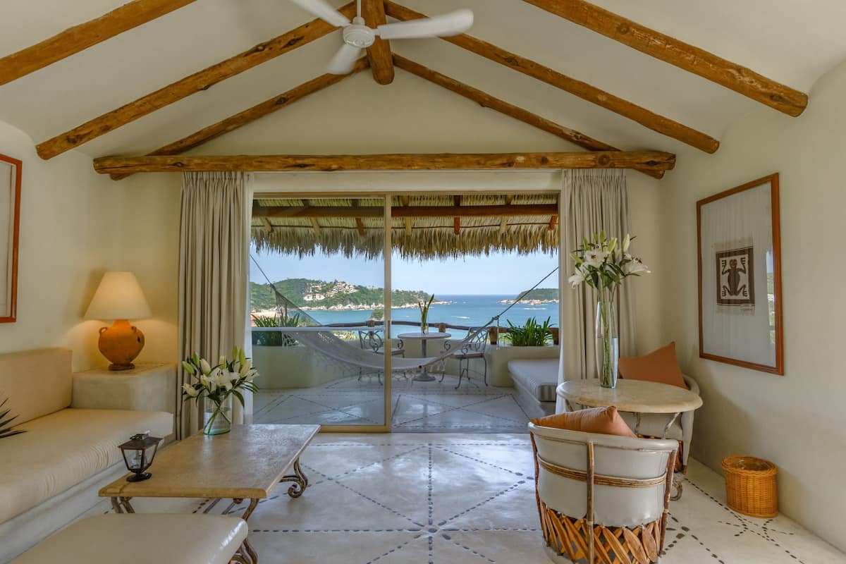 Una habitación con vistas al mar, una hamaca, una mesa con una lámpara y un sofá.