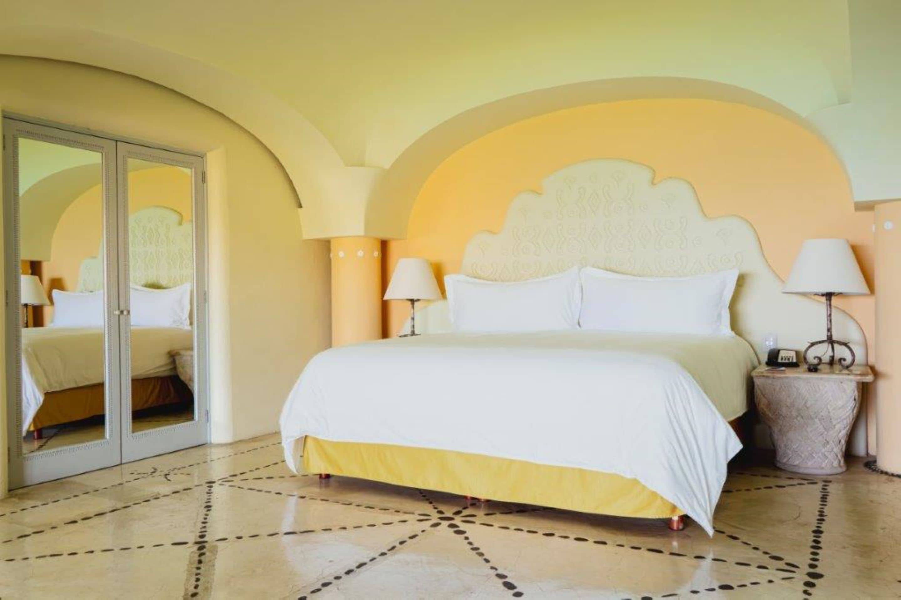 Een hotelkamer met een bed, twee nachtkastjes, een spiegel en een kamer met een patroon.