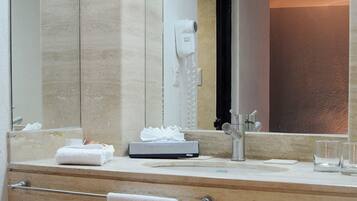 Un baño moderno con un espejo grande, un perchero para toallas, un secador de pelo y un lavabo.