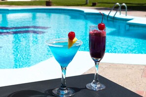 Two cocktails with cherries on a table by a pool. - Hotel Misión Torreón (Torreón)