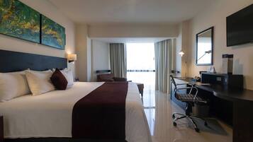 A hotel room with a large bed, a desk, and a view of the outdoors.