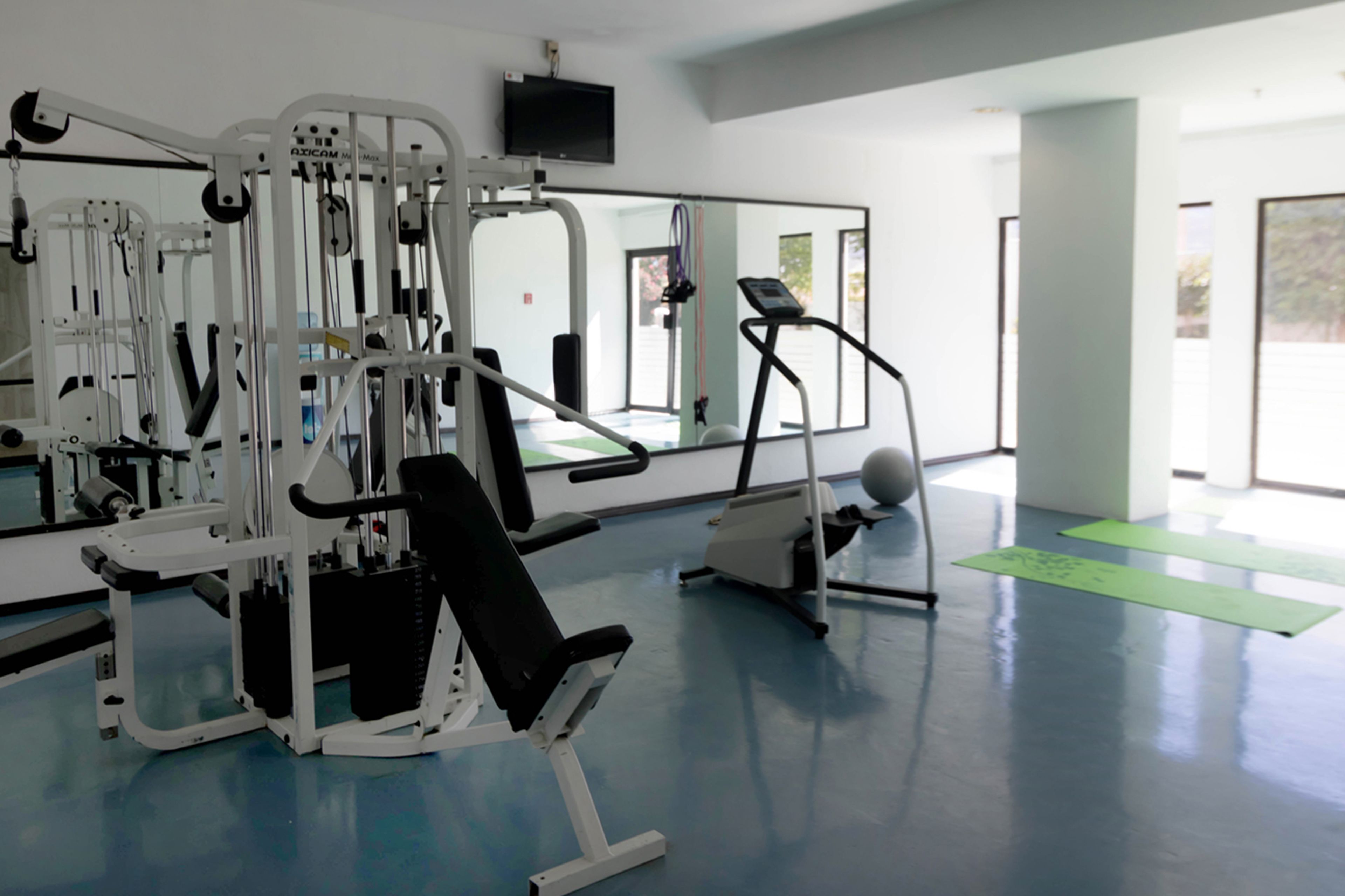 Un gimnasio con equipo de ejercicio, un espejo grande y un ventanal.