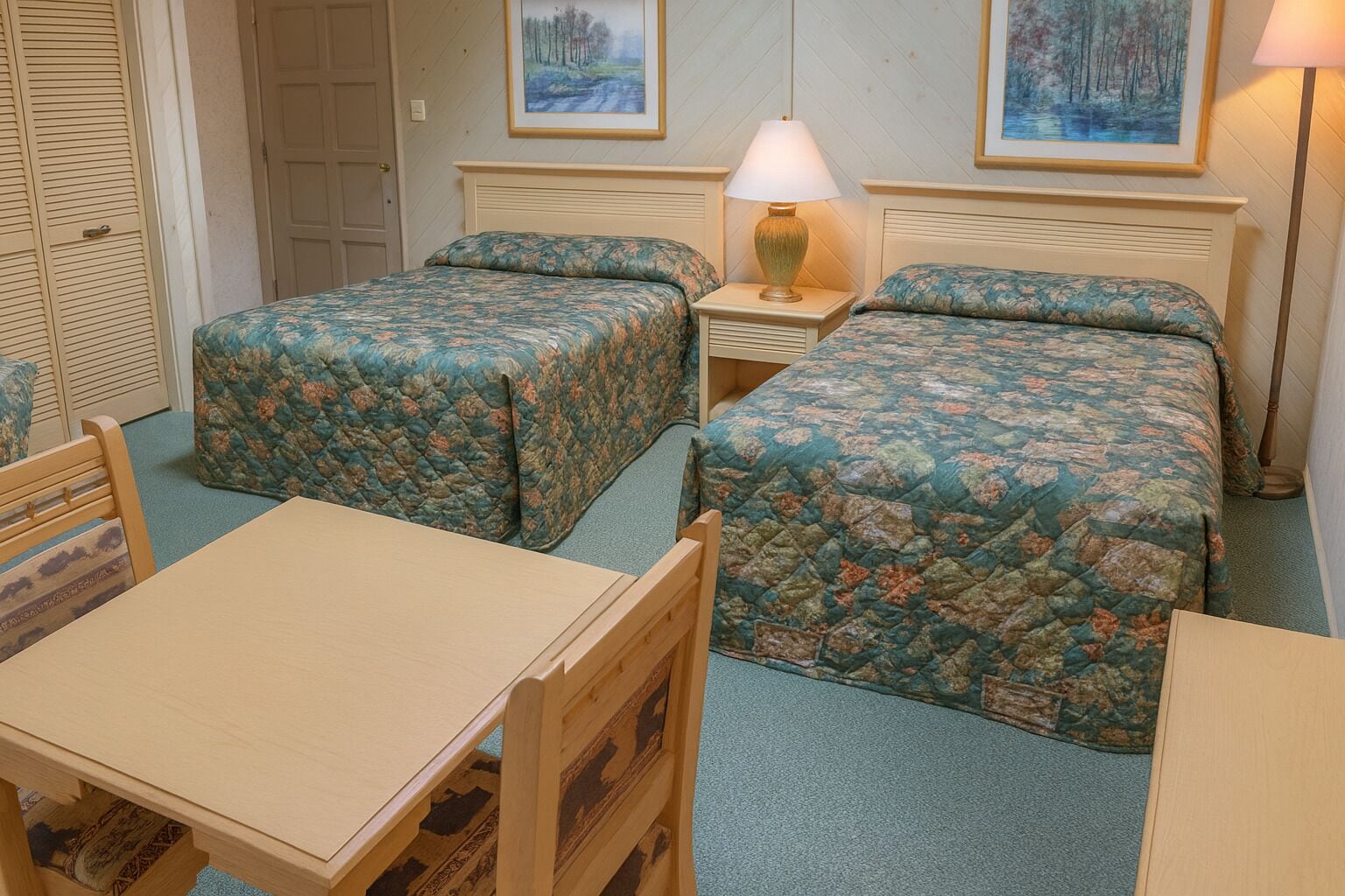 A room with two beds, a table, and a chair.