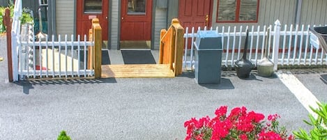 A building with a red door, a small porch, and a white picket fence.