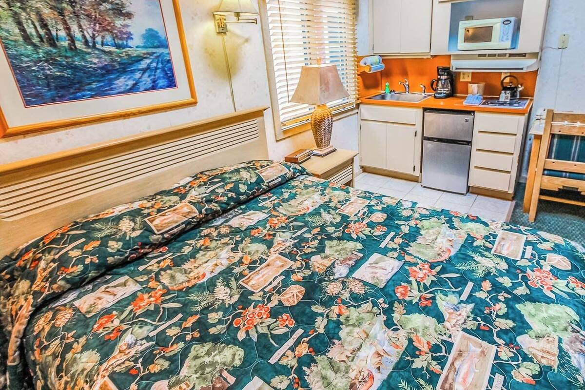 Een hotelkamer met een bed, een bureau, een magnetron en een wastafel.